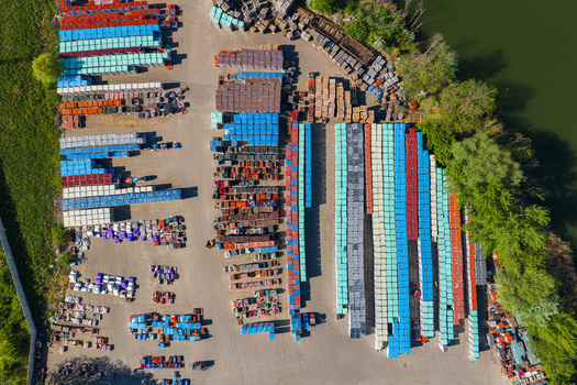 Aerial view of organized rows of colorful industrial crates and pallets in an outdoor storage facility near a riverbank in Kyjov South Moravian Region Czechia.