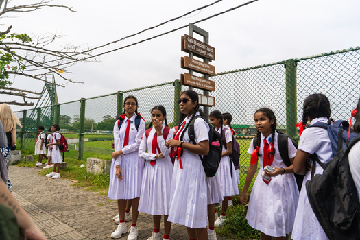 Galle Sri Lanka 07 January 2026 View of schoolgirls in white uniforms with red ties standing near a Galle Municipal Council signpost and a green chain link fence.