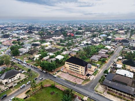 Aerial view of a vibrant urban landscape where dark roofed buildings nestle amidst lush green foliage and winding grey roads under a soft cloudy sky Uyo Akwa Ibom Nigeria. Aerial view of a vibrant urban landscape where dark roofed buildings nestle amidst lush green foliage and winding grey roads under a soft cloudy sky Uyo Akwa Ibom Nigeria.