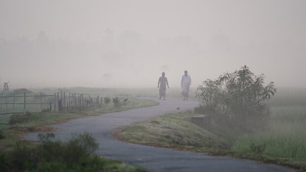 View of men walking on a misty road in Bogura Bangladesh.