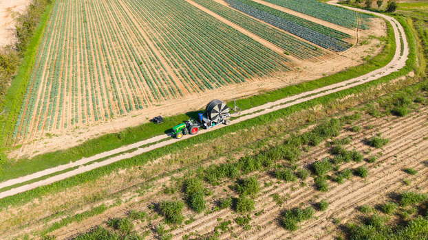 Aerial view of a tractor pulling a reel irrigation system across a cultivated agricultural field in Bettola Zeloforomagno Lombardy Italy. Aerial view of a tractor pulling a reel irrigation system across a cultivated agricultural field in Bettola Zeloforomagno Lombardy Italy.