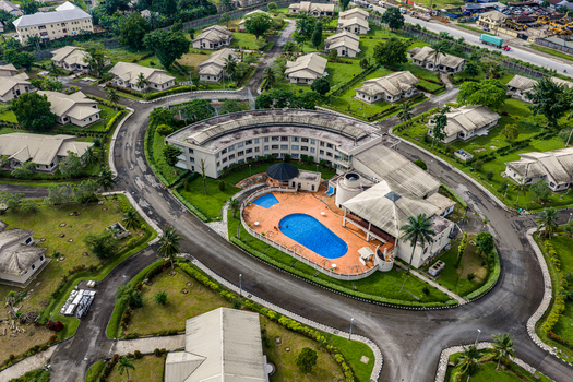 Port Harcourt Nigeria 03 July 2026 Aerial view of a residential complex featuring a curved building a central swimming pool paved roads and surrounding houses with green lawns. Port Harcourt Nigeria 03 July 2026 Aerial view of a residential complex featuring a curved building a central swimming pool paved roads and surrounding houses with green lawns.