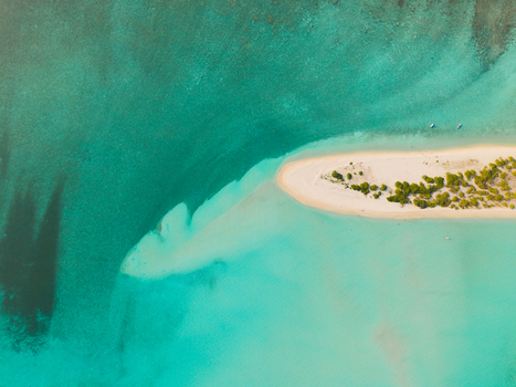 Aerial view of a crescent of pristine white sand fringed with verdant greenery embraced by the turquoise waters of the Indian Ocean Dhidhdhoo Thiladhunmathi Atoll Maldives.