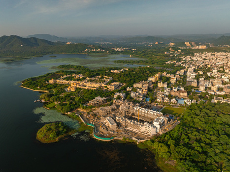 Aerial view of a lakeside development project surrounded by lush greenery and hills in Udaipur Rajasthan India.