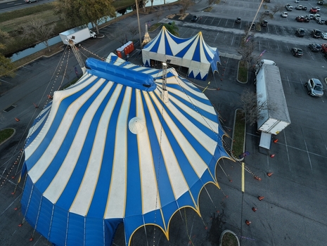 Aerial view of a striking blue and white circus tent pitched against the stark asphalt a temporary splash of color and wonder St. Augustine Florida United States. Aerial view of a striking blue and white circus tent pitched against the stark asphalt a temporary splash of color and wonder St. Augustine Florida United States.