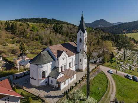Aerial view of the historic white church with its tall steeple surrounded by lush green hills and a cemetery in Valaska Dubova Zilina Region Slovakia. Aerial view of the historic white church with its tall steeple surrounded by lush green hills and a cemetery in Valaska Dubova Zilina Region Slovakia.