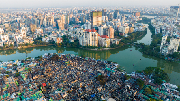 Aerial view of stark contrast between the dense urban skyline and the informal settlement along the river Dhaka Dhaka Division Bangladesh. Aerial view of stark contrast between the dense urban skyline and the informal settlement along the river Dhaka Dhaka Division Bangladesh.