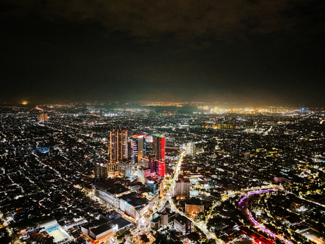 Aerial view of the illuminated cityscape of Surabaya at night featuring glowing skyscrapers dense urban infrastructure and vibrant city lights in Surabaya East Java Indonesia. Aerial view of the illuminated cityscape of Surabaya at night featuring glowing skyscrapers dense urban infrastructure and vibrant city lights in Surabaya East Java Indonesia.