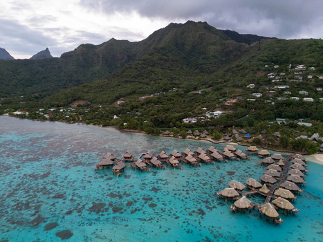 Aerial view of Sofitel Kia Ora Moorea Beach Resort with overwater bungalows over the turquoise lagoon and lush green mountains in Moorea Maiao Windward Islands French Polynesia. Aerial view of Sofitel Kia Ora Moorea Beach Resort with overwater bungalows over the turquoise lagoon and lush green mountains in Moorea Maiao Windward Islands French Polynesia.