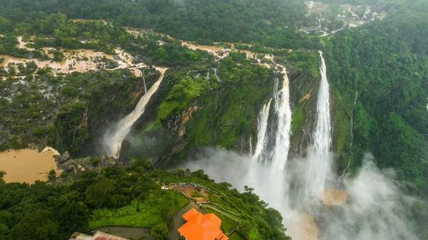 Aerial view of Jog Falls cascading down lush green cliffs with mist and surrounding tropical forest in Kargal Karnataka India.