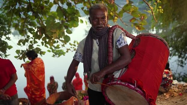 View of a traditional drummer with a large red drum Bangladesh. View of a traditional drummer with a large red drum Bangladesh.
