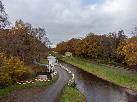 Aerial view of the serene canal framed by autumn trees and the quaint Schuivenhuisje lock under a cloudy sky Schuivenhuisje Overijssel Netherlands. Aerial view of the serene canal framed by autumn trees and the quaint Schuivenhuisje lock under a cloudy sky Schuivenhuisje Overijssel Netherlands.