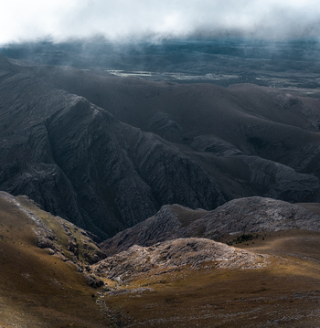View of rugged mountain slopes and deep valleys under a dramatic cloudy sky in the Sierra de La Ventana range Sierra de La Ventana Buenos Aires Province Argentina. View of rugged mountain slopes and deep valleys under a dramatic cloudy sky in the Sierra de La Ventana range Sierra de La Ventana Buenos Aires Province Argentina.