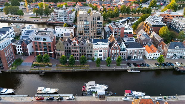 Aerial view of historic and modern buildings along the canal with moored boats and parked cars in Zwolle Overijssel Netherlands.