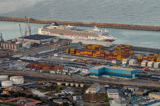 Civitavecchia Italy 23 August 2026 Aerial view of Civitavecchia Port with a large cruise ship docked at the pier colorful shipping containers industrial tanks and rows of parked cars.