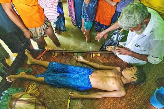 Banshkhali Upazila Chittagong Division Bangladesh 10 July 2026 View of a young boy lying on a mat in a flooded home surrounded by concerned family members during a flood event. Banshkhali Upazila Chittagong Division Bangladesh 10 July 2026 View of a young boy lying on a mat in a flooded home surrounded by concerned family members during a flood event.