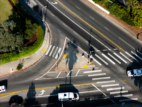 Aerial view of the intersection near Wilshire Country Club with asphalt roads white lane markings crosswalks and the shadow of a palm tree in Los Angeles California United States. Aerial view of the intersection near Wilshire Country Club with asphalt roads white lane markings crosswalks and the shadow of a palm tree in Los Angeles California United States.