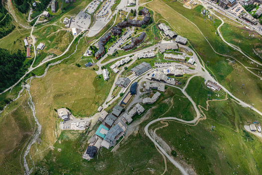 Aerial view of the Breuil Cervinia ski resort area featuring alpine buildings winding roads and green mountain slopes in Breuil Cervinia Aosta Valley Italy. Aerial view of the Breuil Cervinia ski resort area featuring alpine buildings winding roads and green mountain slopes in Breuil Cervinia Aosta Valley Italy.