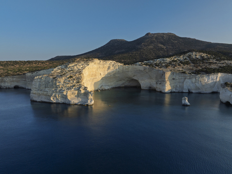 Aerial view of the white volcanic rock formations and sea caves of Sarakiniko beach surrounded by deep blue Aegean Sea waters in Milos Greece. Aerial view of the white volcanic rock formations and sea caves of Sarakiniko beach surrounded by deep blue Aegean Sea waters in Milos Greece.