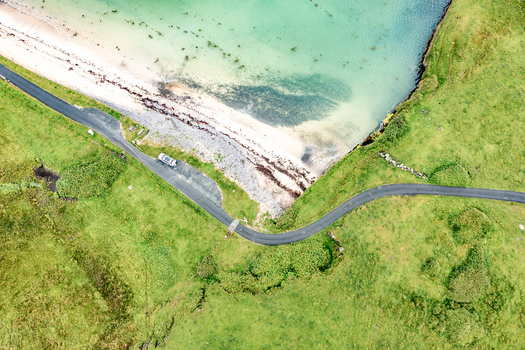 Aerial view of St John s Point Beach featuring turquoise water a sandy shoreline and a winding coastal road cutting through green fields in Dunkineely County Donegal Ireland.