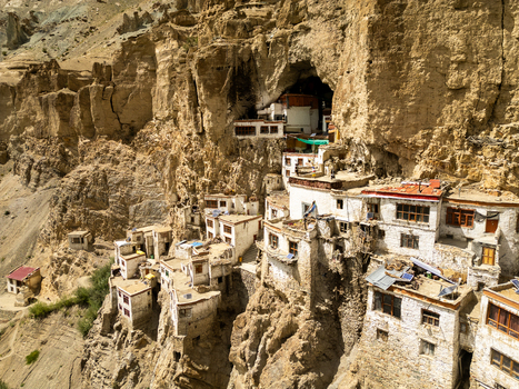 Aerial view of Phukthal Gompa a historic Buddhist monastery built into a cliffside cave featuring white washed buildings and traditional architecture in Phukthal Ladakh India.