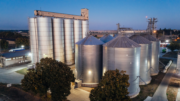Aerial view of industrial grain silos with metallic storage tanks illuminated at dusk in Sremska Mitrovica Vojvodina Serbia. Aerial view of industrial grain silos with metallic storage tanks illuminated at dusk in Sremska Mitrovica Vojvodina Serbia.