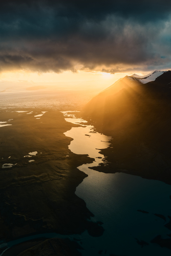 Aerial view of Jokulsarlon glacier lagoon at sunset with dramatic golden light reflecting on the water dark mountain silhouettes and moody clouds Sveitarfelagid Hornafjordur Iceland. Aerial view of Jokulsarlon glacier lagoon at sunset with dramatic golden light reflecting on the water dark mountain silhouettes and moody clouds Sveitarfelagid Hornafjordur Iceland.
