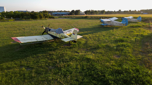 Serbia 03 September 2023 Aerial view of two agricultural biplanes parked on a grassy field during golden hour with long shadows and a rural landscape in the background.
