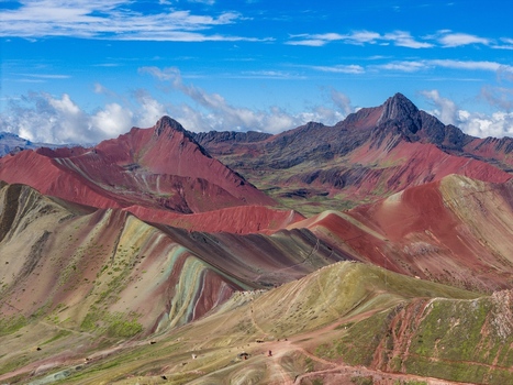 Aerial view of Vinicunca Rainbow Mountain with its vibrant mineral striped slopes rugged mountain peaks and winding trails under a bright blue sky in Cusco Cuzco Peru. Aerial view of Vinicunca Rainbow Mountain with its vibrant mineral striped slopes rugged mountain peaks and winding trails under a bright blue sky in Cusco Cuzco Peru.