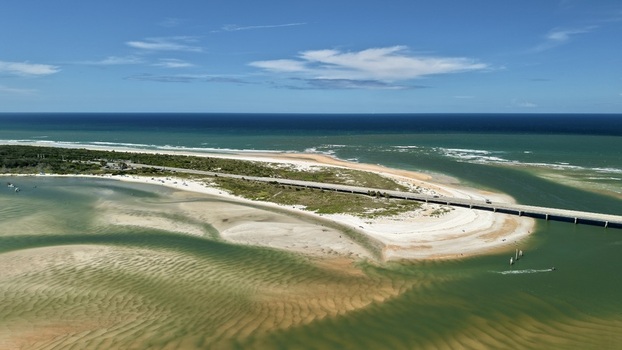 Aerial view of Matanzas Inlet featuring sandy shoals turquoise waters and a bridge crossing the coastal landscape in St. Johns County Florida United States. Aerial view of Matanzas Inlet featuring sandy shoals turquoise waters and a bridge crossing the coastal landscape in St. Johns County Florida United States.