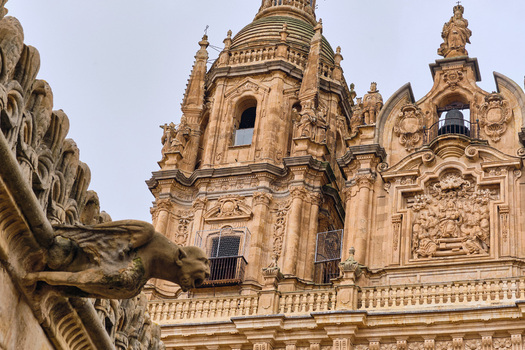 Salamanca Spain 29 November 2025 View of the ornate Baroque towers of La Clerecia Iglesia del Espiritu Santo and a stone gargoyle under a cloudy sky.
