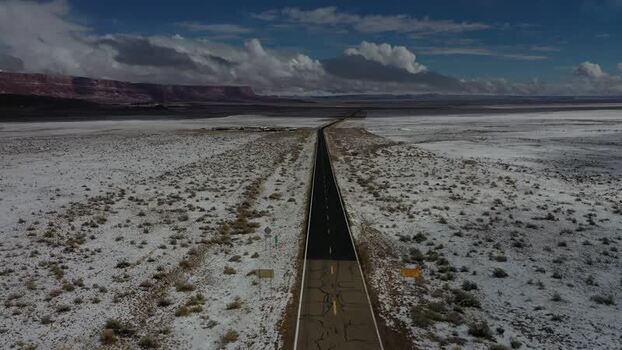 View of a snow covered desert road and distant mountains United States. View of a snow covered desert road and distant mountains United States.