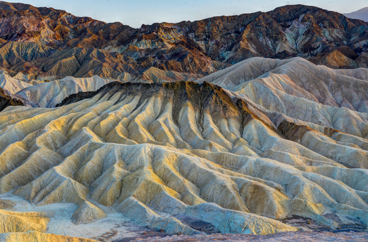 View of the rugged eroded badlands of Death Valley National Park with colorful sedimentary layers and dramatic shadows in Death Valley California United States.