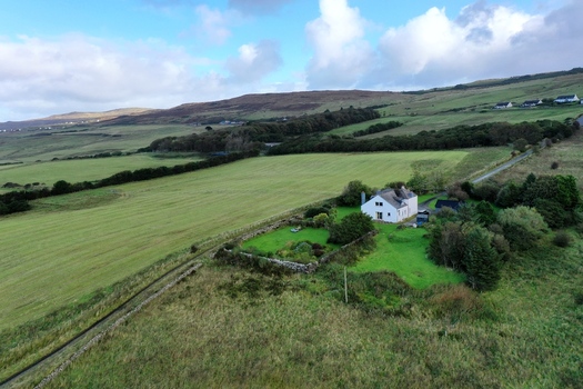 Aerial view of a white house nestled in the green fields of the Scottish countryside with rolling hills and a cloudy sky in Stein Scotland United Kingdom. Aerial view of a white house nestled in the green fields of the Scottish countryside with rolling hills and a cloudy sky in Stein Scotland United Kingdom.