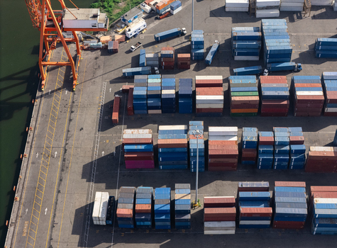 Aerial view of the industrial port featuring rows of colorful shipping containers a large orange crane and paved terminal grounds in Bajos de Haina San Cristobal Provinc Dominican Republic.