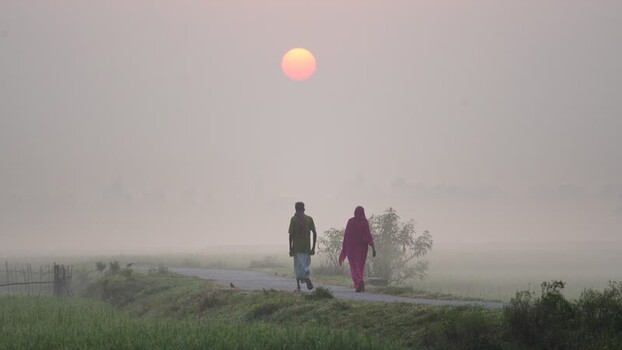 View of a couple walking on a rural path at sunrise Bangladesh.