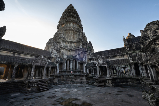View of Angkor Wat temple complex with its iconic central tower ancient stone carvings and weathered sandstone walls under a clear sky in Krong Siem Reap Siem Reap Province Cambodia. View of Angkor Wat temple complex with its iconic central tower ancient stone carvings and weathered sandstone walls under a clear sky in Krong Siem Reap Siem Reap Province Cambodia.