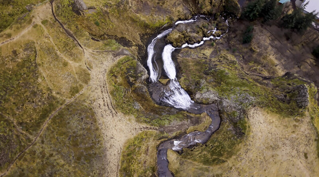 Aerial view of a waterfall cascading through a rocky moss covered landscape in Kirkjubaejarklaustur Iceland.