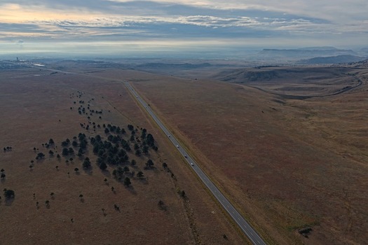 Aerial view of a highway stretching through the dry grassy plains and rolling hills of the landscape near Golden Colorado United States.