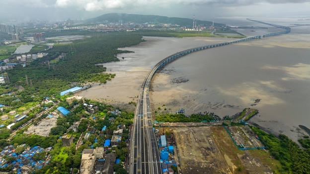 Aerial view of Atal Bihari Vajpayee Sewri Nhava Sheva Atal Setu bridge spanning the bay with industrial coastal areas and greenery in the background Mumbai Maharashtra India. Aerial view of Atal Bihari Vajpayee Sewri Nhava Sheva Atal Setu bridge spanning the bay with industrial coastal areas and greenery in the background Mumbai Maharashtra India.