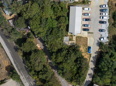 Aerial view of a parking lot with several cars parked in rows next to a modern building surrounded by dense green trees and a paved road in Istanbul Istanbul Turkey. Aerial view of a parking lot with several cars parked in rows next to a modern building surrounded by dense green trees and a paved road in Istanbul Istanbul Turkey.