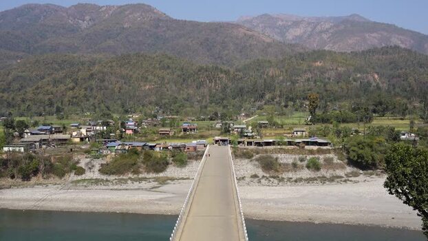 View of a long concrete bridge leading to a village Nepal.