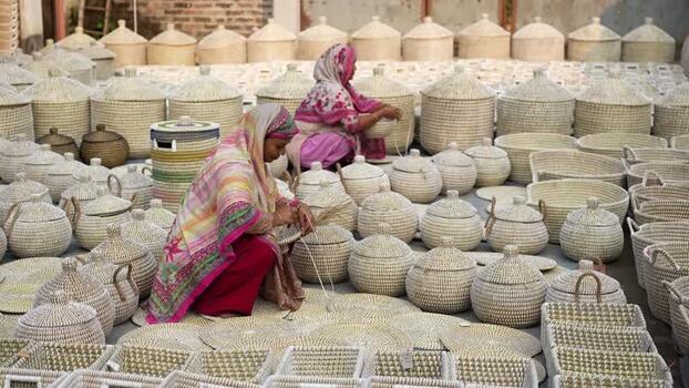 View of women weaving handmade baskets in Bogura Bangladesh. View of women weaving handmade baskets in Bogura Bangladesh.