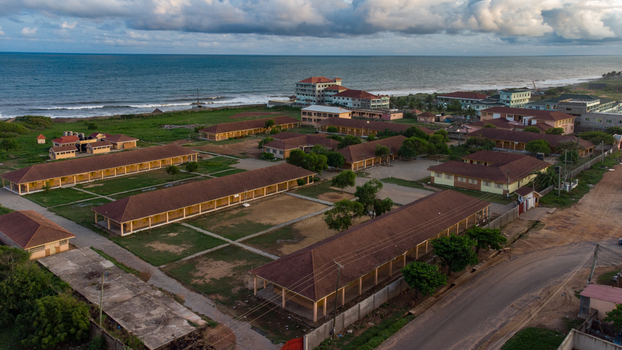 Aerial view of the Teshie school complex featuring brown roofed buildings and grassy courtyards situated along the coastline in Accra Greater Accra Region Ghana.