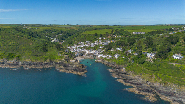 Aerial view of the historic coastal village with its small harbor boats and turquoise sea surrounded by lush green hills in Polperro Cornwall United Kingdom. Aerial view of the historic coastal village with its small harbor boats and turquoise sea surrounded by lush green hills in Polperro Cornwall United Kingdom.