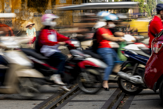 Hanoi Ha Noi Vietnam 11 November 2025 View of motorbikes passing through the narrow Train Street with a woman sitting in the background.