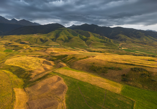 Aerial view of the Chon Kemin valley with rolling golden and green hills under dramatic storm clouds in Kaindy Chuy Province Kyrgyzstan.