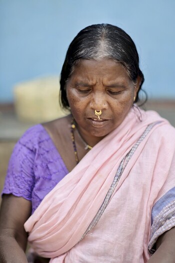 Odisha India 26 March 2026 View of an Indian woman with a nose ring dressed in a pink shawl and purple blouse lost in thought against a light blue wall backdrop. Odisha India 26 March 2026 View of an Indian woman with a nose ring dressed in a pink shawl and purple blouse lost in thought against a light blue wall backdrop.