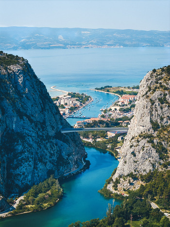 Aerial view of the Cetina River canyon flowing through the historic town of Omis with rocky cliffs a bridge and the Adriatic Sea in Omis Split Dalmatia County Croatia. Aerial view of the Cetina River canyon flowing through the historic town of Omis with rocky cliffs a bridge and the Adriatic Sea in Omis Split Dalmatia County Croatia.