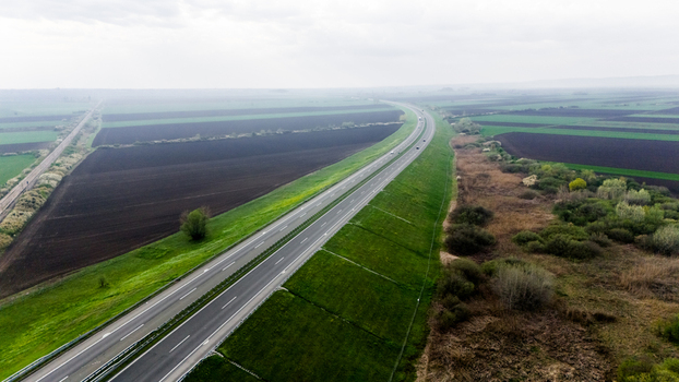 Aerial view of the highway cutting through the landscape contrasting with the lush green embankments and the vast dark fields beyond Sremska Mitrovica Vojvodina Serbia. Aerial view of the highway cutting through the landscape contrasting with the lush green embankments and the vast dark fields beyond Sremska Mitrovica Vojvodina Serbia.